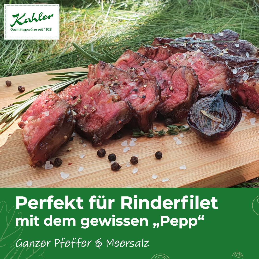 Aufgeschnittenes Rinderfilet auf Holzbrett mit grobem Meersalz, schwarzen Pfefferkörnern, Rosmarinzweigen und gegrillter roter Zwiebel und Kahler Logo