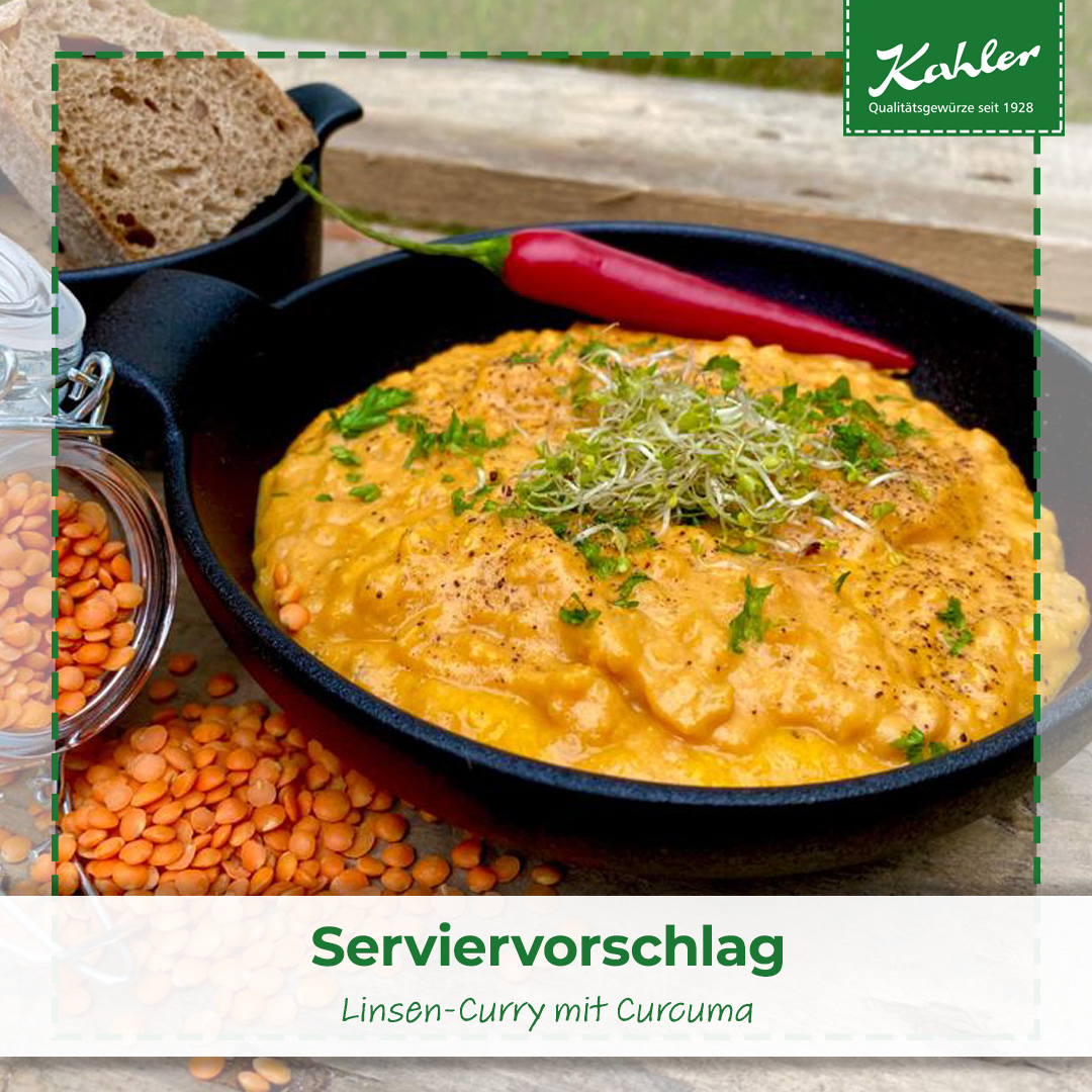 Schwarze Pfanne mit Linsen-Curry, garniert mit Sprossen und Petersilie, daneben ein roter Chili und ein Stück Brot