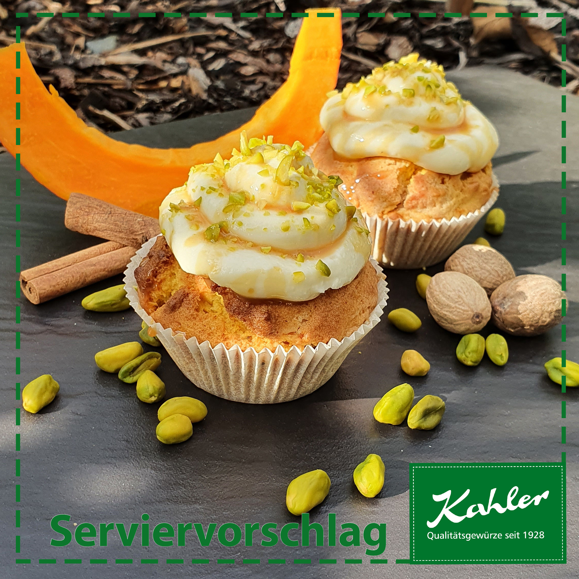 Zwei Muffins mit weißem Topping und Pistazienstückchen auf dunkler Platte mit Zimtstangen, Muskatnüssen, Pistazien und Kürbisscheiben, darunter das Logo Kahler